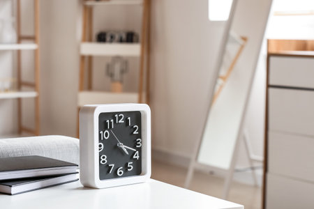 Clock with books on table in room