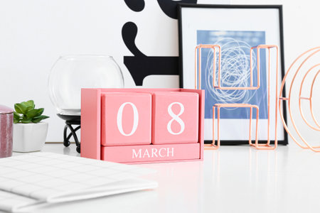 Cube calendar with date MARCH 8 and frame on table in room, closeup