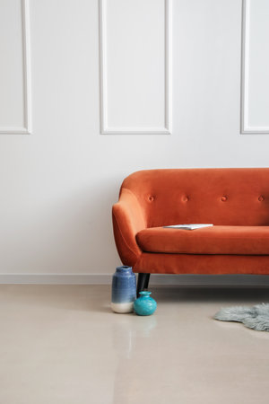 Stylish brown sofa, vases and magazine near light wallの写真素材