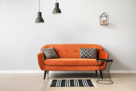 Stylish brown sofa with pillows and table near light wallの写真素材