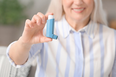 Mature woman with inhaler at homeの写真素材