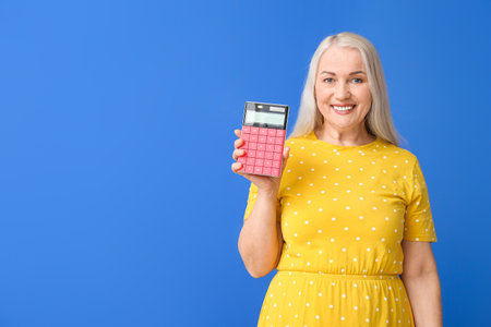 Mature woman with calculator on color backgroundの写真素材