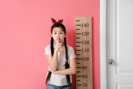 Little girl measuring height near color wallの写真素材