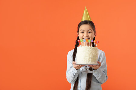 Cute little girl with birthday cake on color backgroundの写真素材