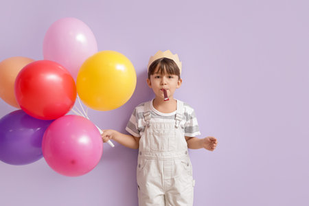 Cute little boy with balloons celebrating Birthday on color backgroundの写真素材