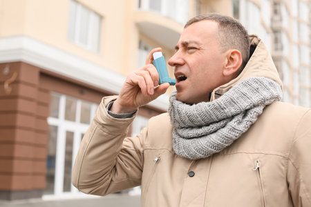 senior man with inhaler having asthma attack outdoorsの写真素材