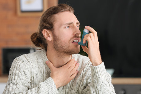 Young man with inhaler having asthma attack at home