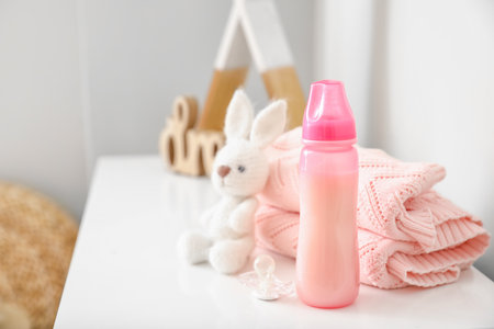 Bottle of milk for baby with toy and clothes on shelfの写真素材