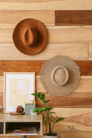 Stylish workplace and hats hanging on wooden wall
