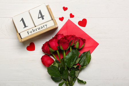 Cube calendar with date 14 FEBRUARY, roses, envelope and hearts on white wooden backgroundの写真素材