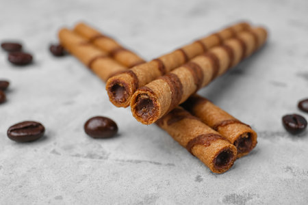 Delicious rolled wafer cookies and coffee beans on grunge background, closeupの写真素材