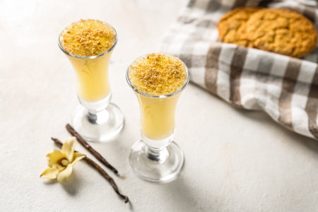 Shots of delicious pudding with cookie crumbs and vanilla sticks on white table