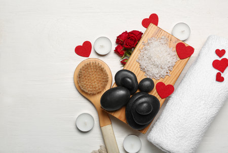 Beautiful spa composition for Valentine's Day with brush, stones, rose flowers, sea salt and candles on white wooden backgroundの写真素材