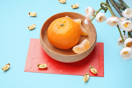 Bowl with mandarin, envelope, sakura and Chinese symbols on blue background, closeup. new year celebrationの写真素材