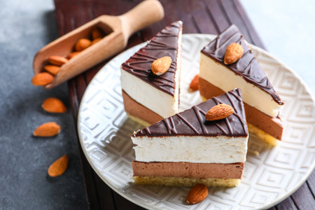 Board with plate of birds milk cake pieces, scoop and almond nuts on gray backgroundの写真素材