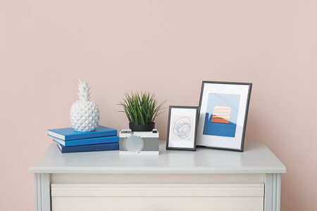 Stylish decor on chest of drawers near color wall