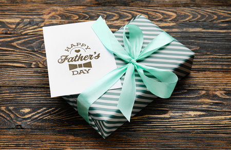 Gift box and greeting card for Father's Day celebration on wooden background