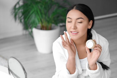 Beautiful Asian woman applying cream in bathroomの写真素材