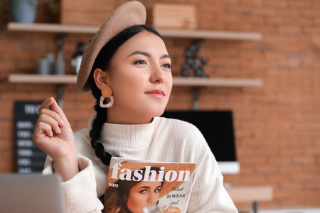 Beautiful Asian woman with fashion magazine at homeの写真素材