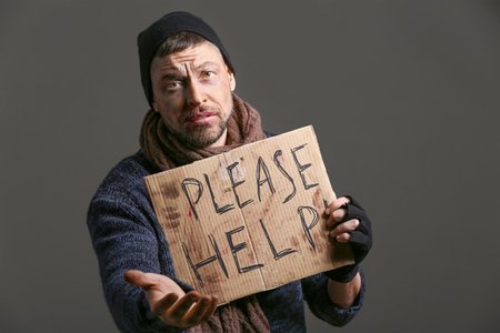 Portrait of begging homeless man on dark backgroundの写真素材