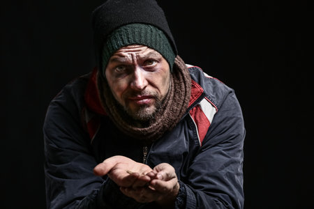 Portrait of poor homeless man on dark backgroundの写真素材