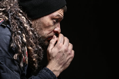 Portrait of poor homeless man on dark background