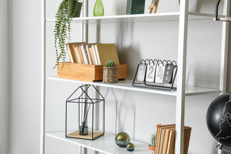Modern book shelf with decor near light wallの写真素材