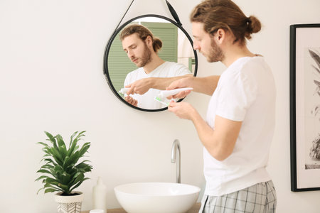 Young man brushing teeth in bathroomの写真素材