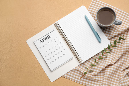 Calendar with cup of coffee and notebook on color backgroundの写真素材