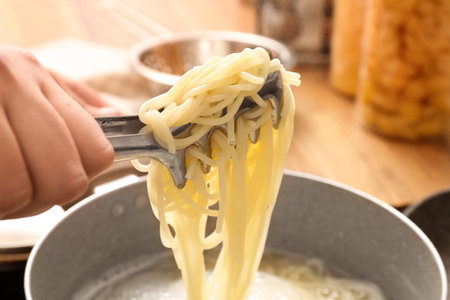 Woman preparing delicious pasta in kitchen, closeupの写真素材