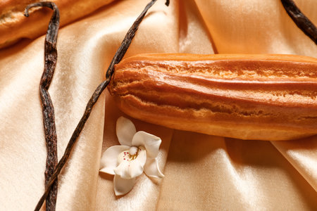 Sweet eclair and vanilla sticks on fabric backgroundの写真素材