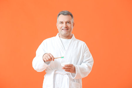 Mature man brushing teeth on color backgroundの写真素材