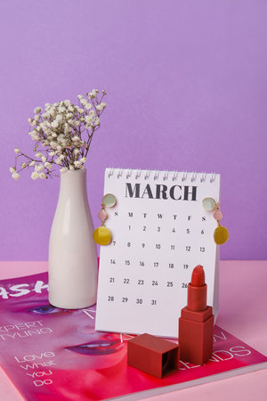 Calendar with female accessories, flowers and fashion magazine on color background. International Women's Day celebrationの写真素材