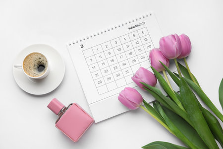 Calendar with flowers, perfume bottle and cup of coffee on light background. International Women's Day celebrationの写真素材