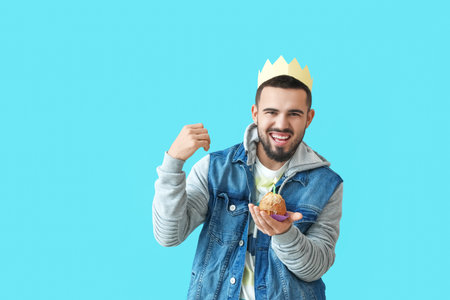 Happy young man with birthday cupcake on color backgroundの写真素材