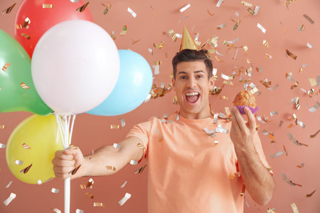 Handsome man celebrating birthday on color backgroundの写真素材