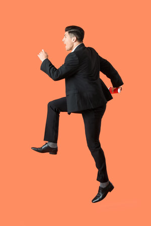 Jumping handsome man with cup of coffee on color backgroundの写真素材