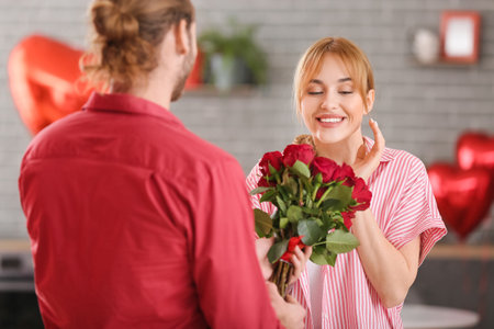 Young man greeting his girlfriend on Valentine's Day at homeの写真素材