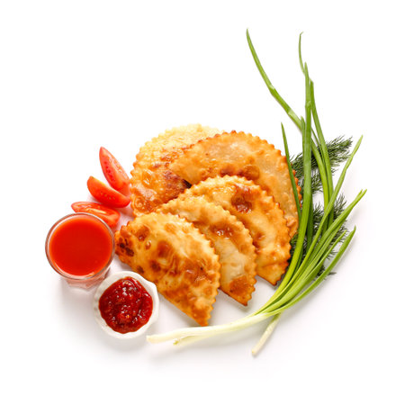 Plate with tasty chebureks, onion, sauce, tomato slices and juice on white backgroundの写真素材