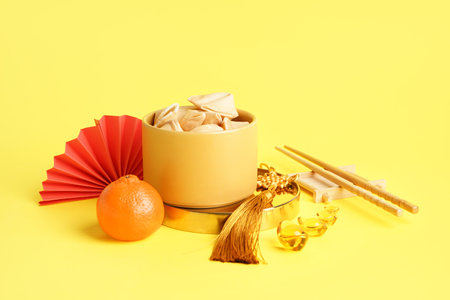 Bowl of fortune cookies, mandarin and Chinese symbols on yellow backgroundの写真素材