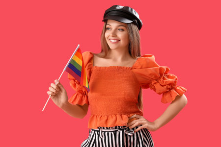 Beautiful young woman in hat with LGBT flag on red backgroundの写真素材