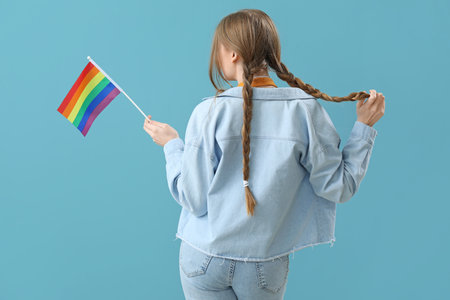 Beautiful young woman with LGBT flag on blue background, back viewの写真素材