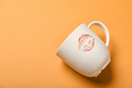 Cup with lipstick kiss mark on orange backgroundの写真素材