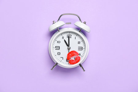 Vintage alarm clock with lipstick kiss mark on lilac backgroundの写真素材
