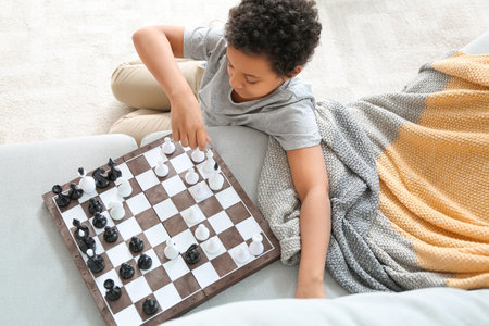 Cute African-American boy playing chess at home