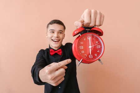 Teenager with alarm clock on color backgroundの写真素材