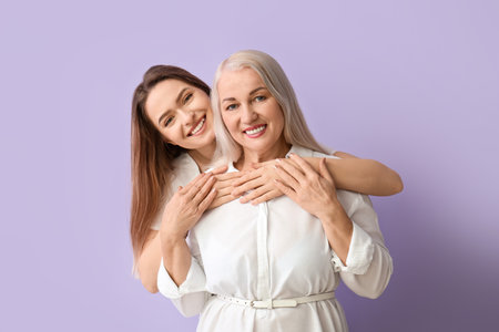 Portrait of young woman and her mother on color backgroundの写真素材