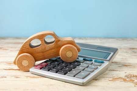 Calculator with car figure on color wooden backgroundの写真素材