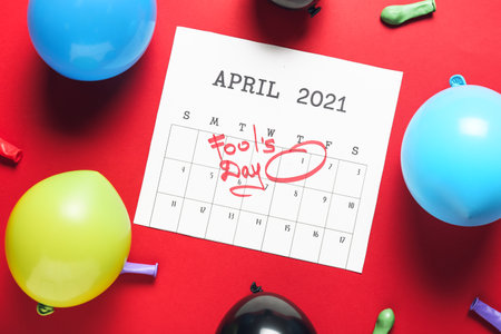 Calendar with marked date of April Fool's Day and party decor on color backgroundの写真素材