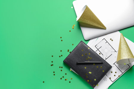 Party hats with laptop, drawings and office stationery on color backgroundの写真素材